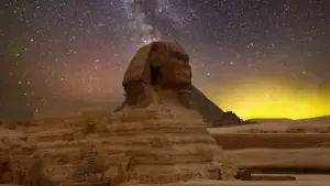 Fotografía nocturna de la Gran Esfinge de Guiza iluminada, con el cielo lleno de estrellas.