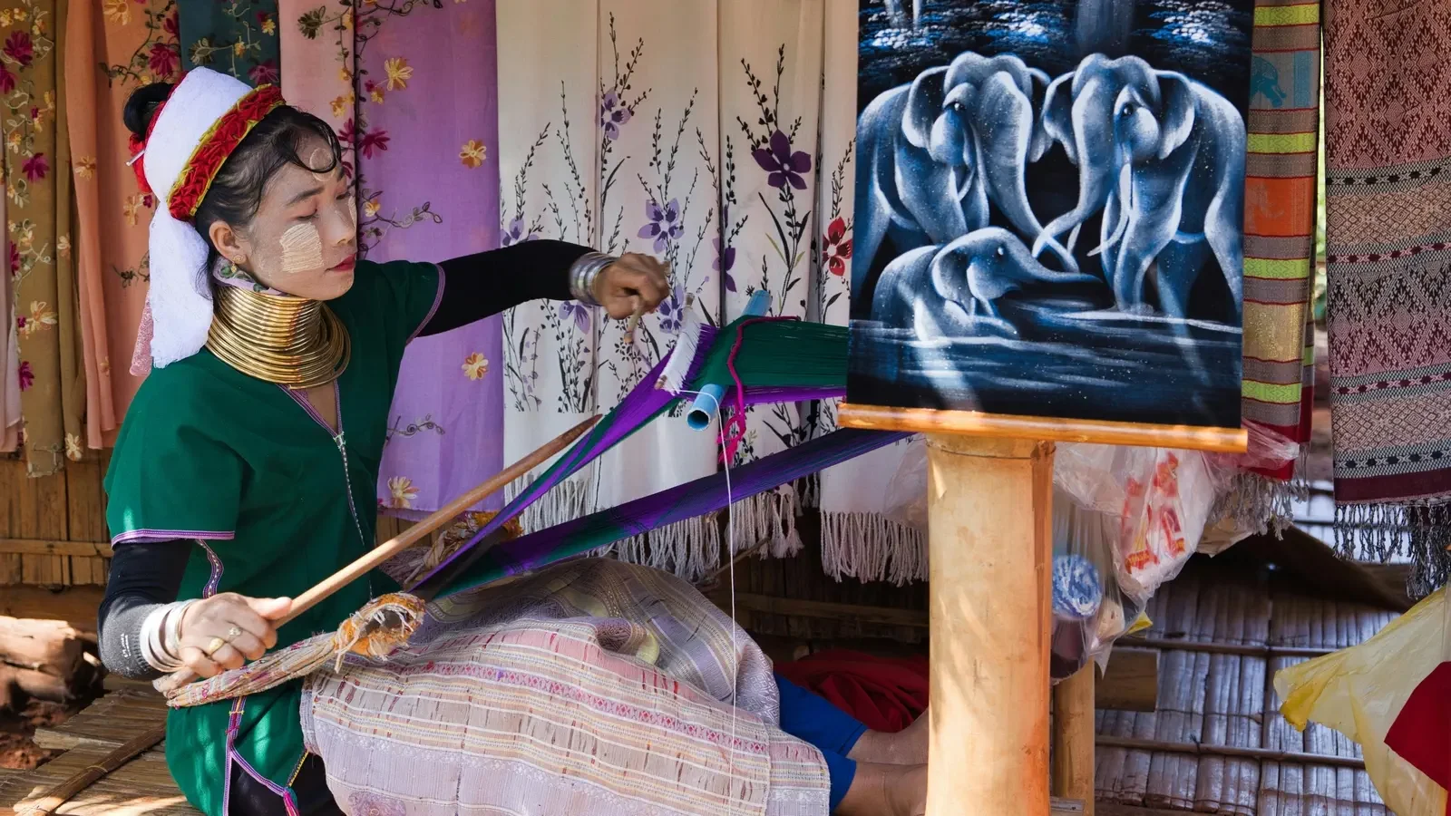 Woman weaving in the traditional style in Chiang Mai, Thailand surrounded by handcrafts.