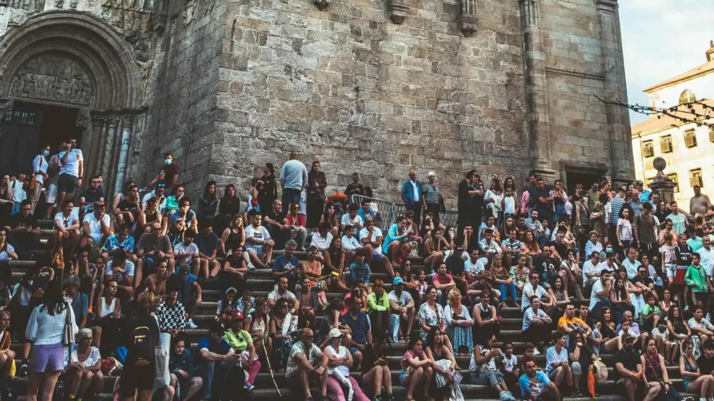 A huge crowd of people sitting on the steps of Santiago Cathedral after completing their Camino. Photo by jokassis on Pexels.com.