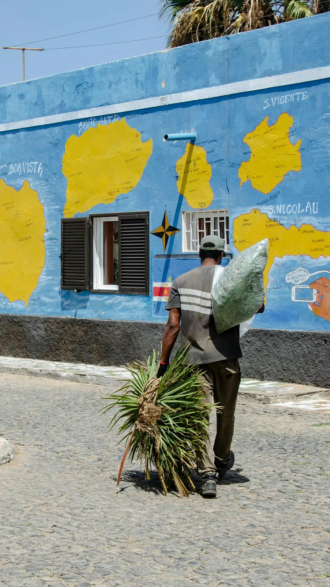 Hombre local caminando frente a mural colorido con mapa de Cabo Verde en Boa Vista — foto de Piotrek Wilk (Pexels)