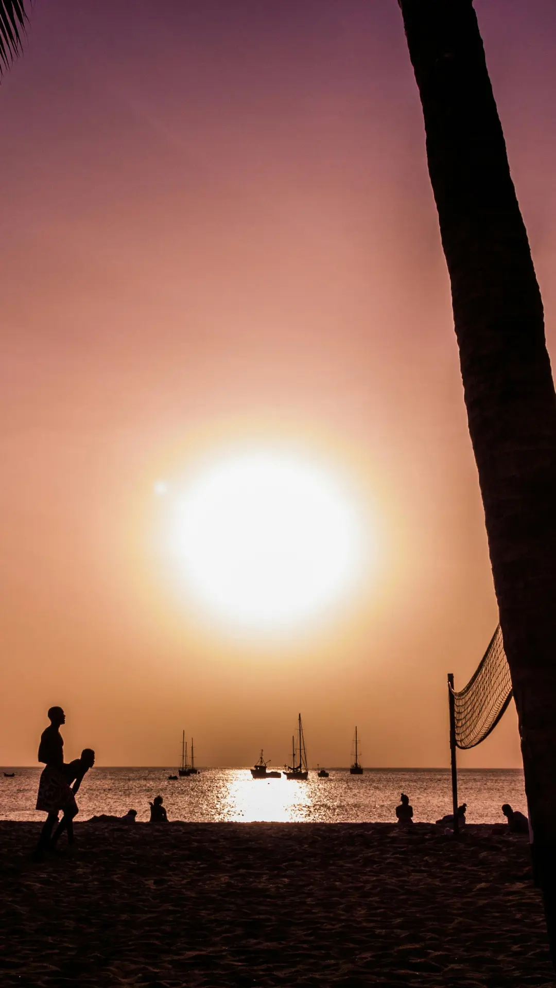 Atardecer dorado con red de vóley, barcos y bañistas en playa de Cabo Verde — foto de Thomas Schwaak (Pexels)